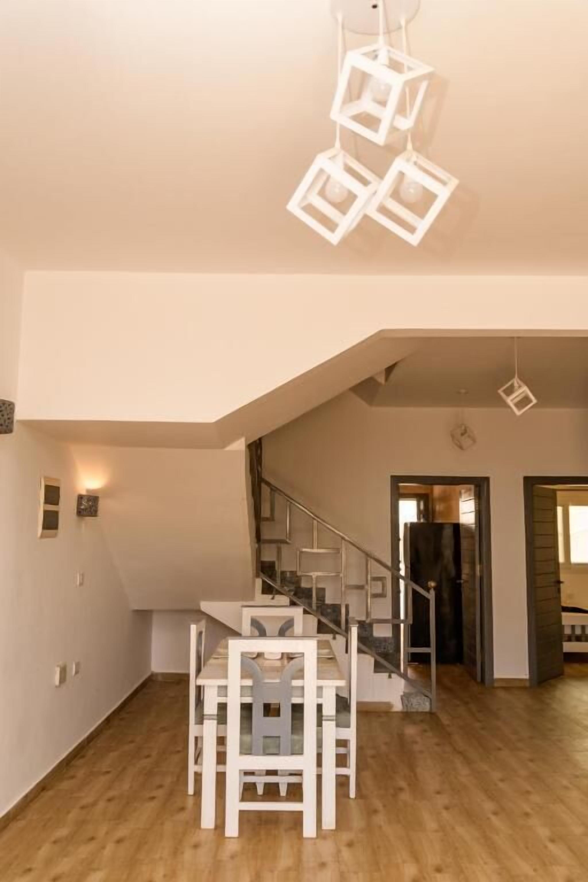 Ein geräumiger Raum mit Holzboden, einer Treppe und einem Essbereich mit heller Möbel.