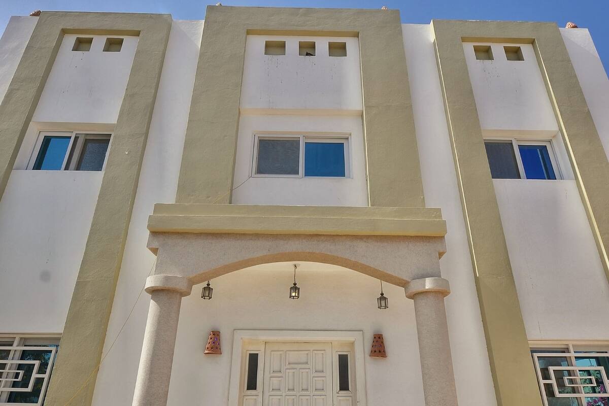 A building with a central entrance, flanked by columns, and a door with a decorative arch above.