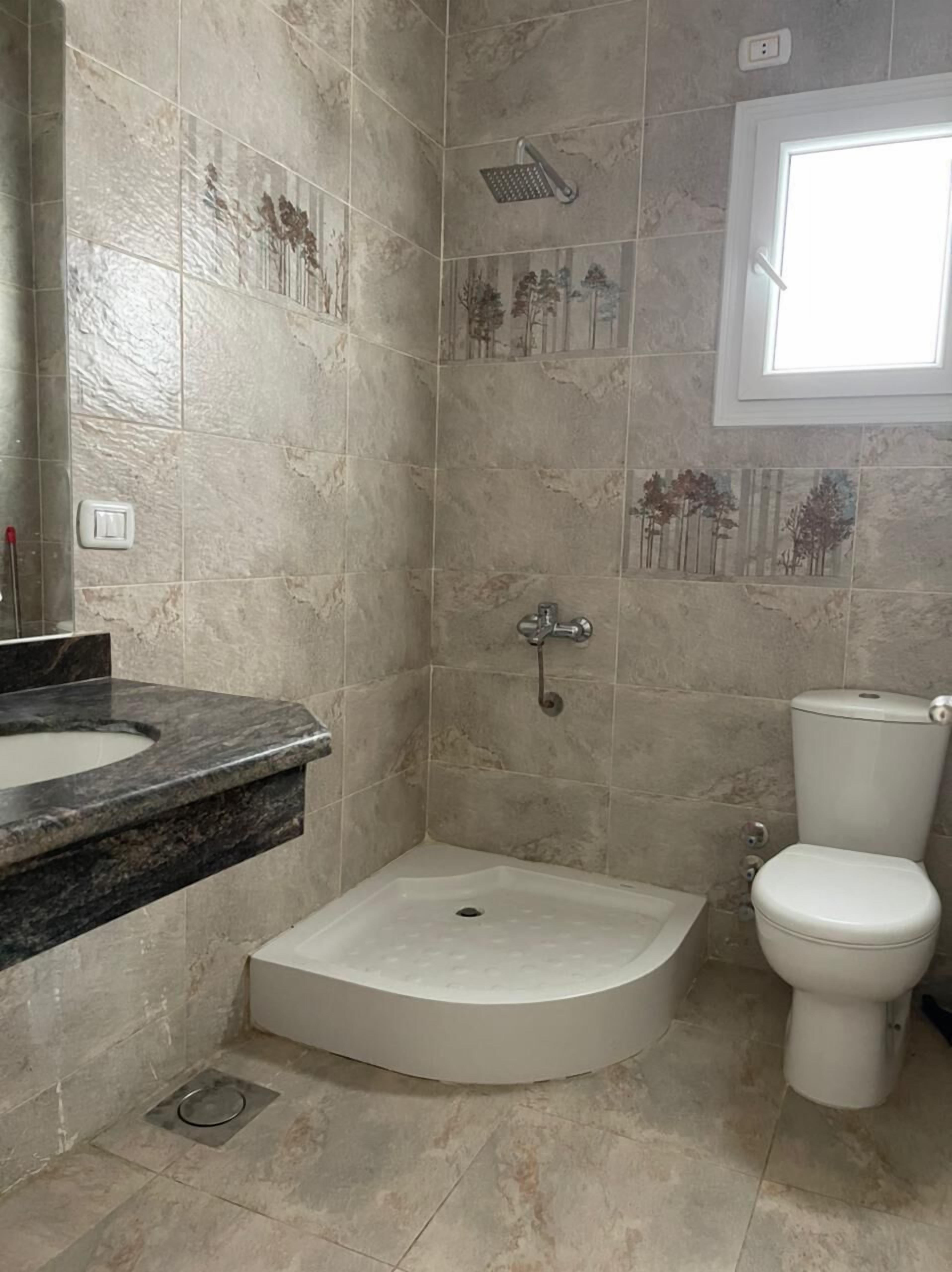 A bathroom with a shower, toilet, and sink.