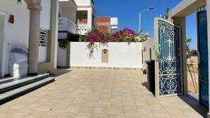 A building with a gated entrance, a tiled patio, and a white wall with a small window. - Elite Residence (Dahab)