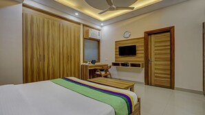 Quarto com cama, escrivaninha, cadeira, televisão e armários.