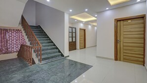 Um interior moderno com escadaria de mármore, portas de madeira e iluminação embutida no teto.