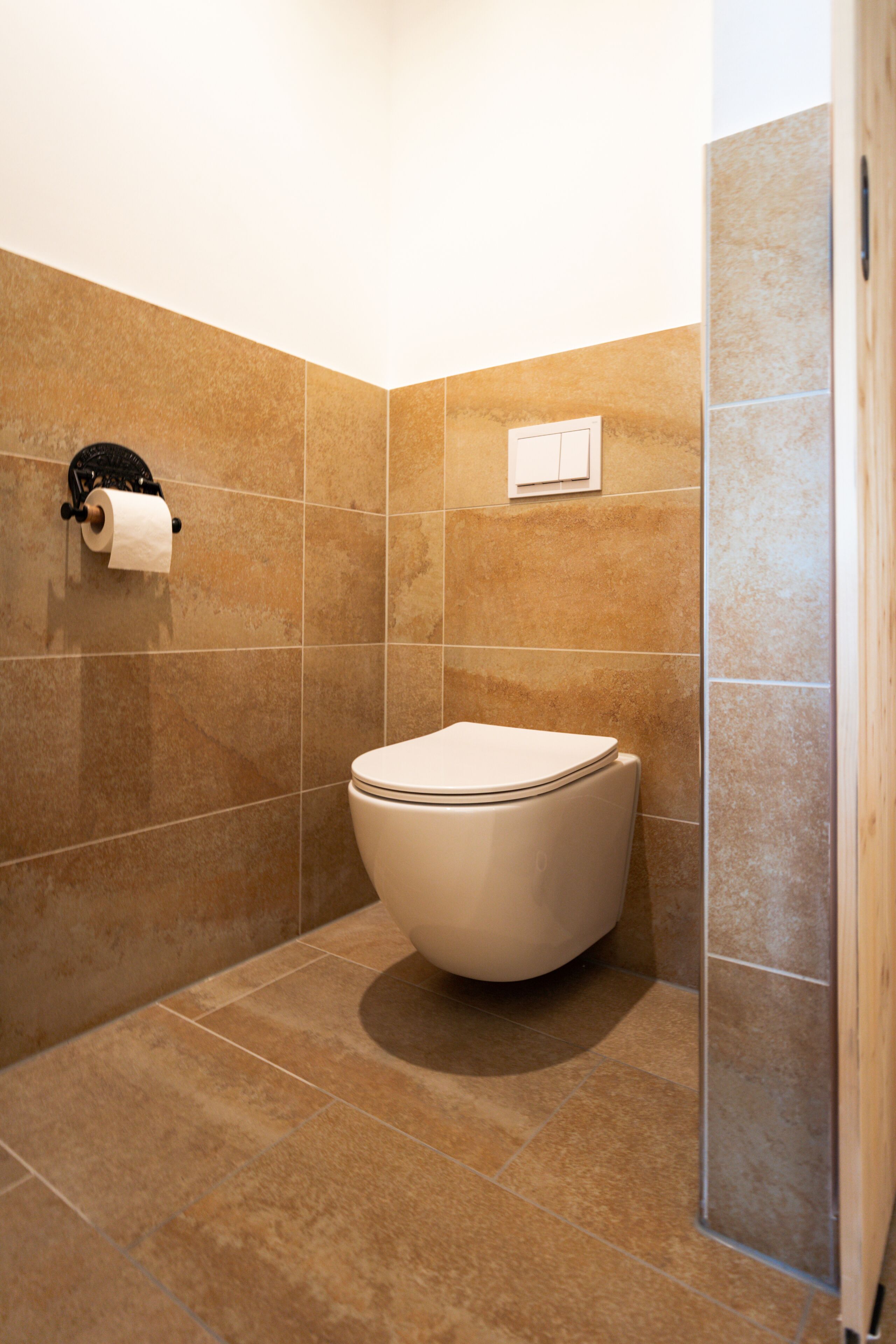 Ein Badezimmer mit Toilette, Toilettenpapierhalter und Duschbereich.