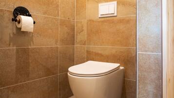Ein Badezimmer mit Toilette, Toilettenpapierhalter und Duschbereich.