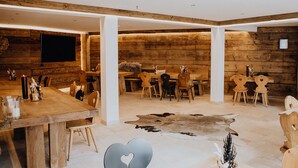 A spacious dining area with wooden tables and chairs, a large flat-screen TV mounted on the wall, and a unique cowhide rug on the floor. - Der Postwirt (Kipfenberg)