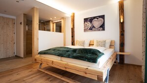 A wooden bed with a green blanket, a wooden headboard, and a wall-mounted picture of a heart. - Der Postwirt (Kipfenberg)