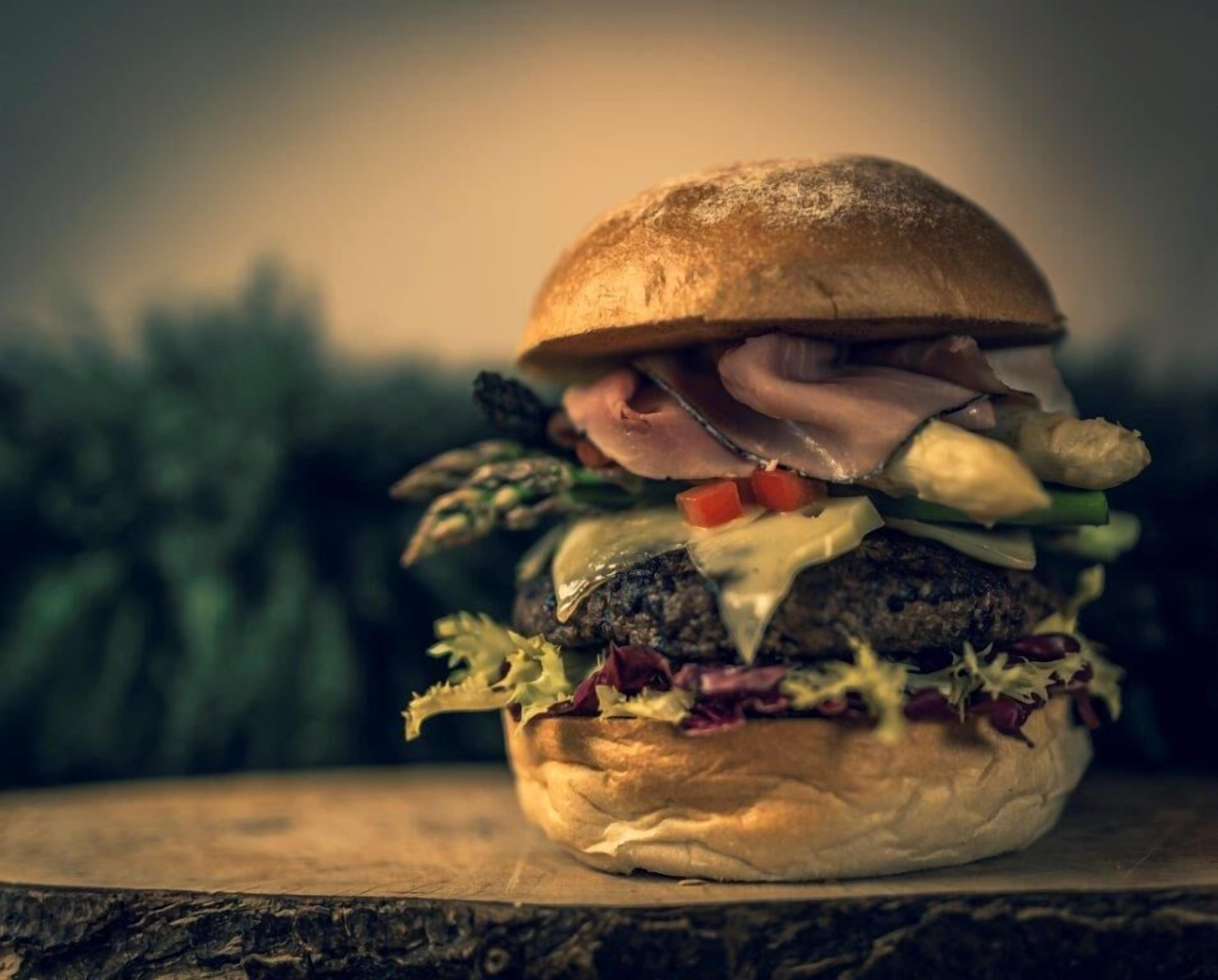 A burger on a wooden surface with a blurred background.