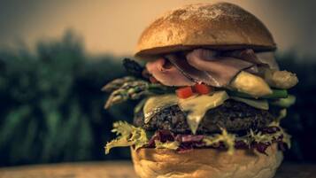 Ein Burger auf einer Holztischfläche, Hintergrund unscharf.