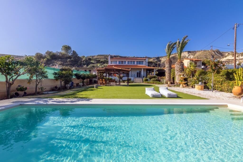 A clear swimming pool with a house in the background.