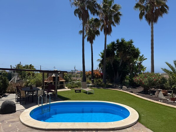 A swimming pool surrounded by a patio area with a table and chairs, palm trees, and a view of the ocean. - Romantic vacation home on an idyllic, quiet finca (Granadilla)