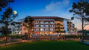 Un hotel de varios pisos con zonas de estar al aire libre, balcones con plantas y un jardín cuidado.