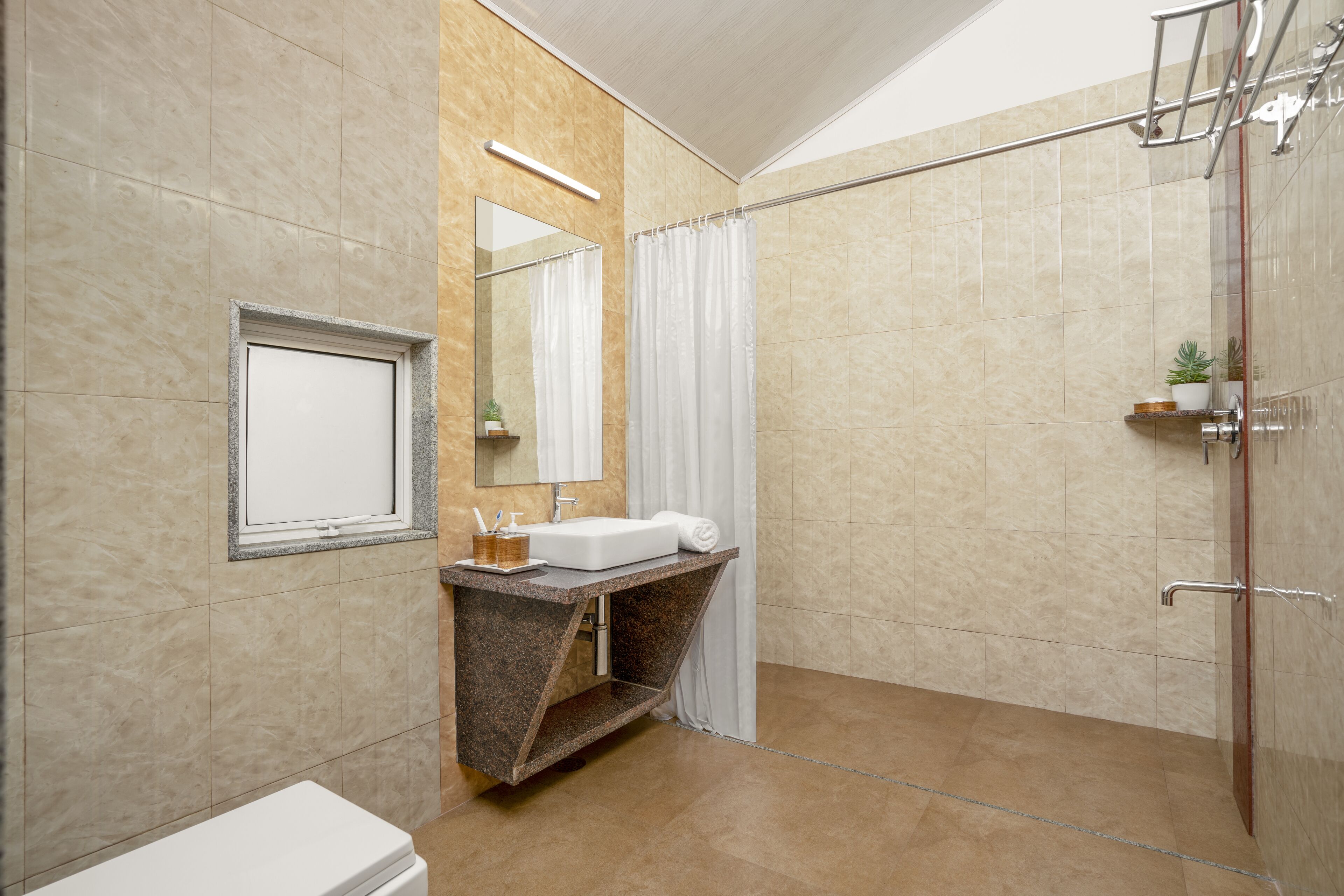 Un baño moderno con lavamanos de mármol, ducha con puerta de vidrio y espejo con marco de madera.