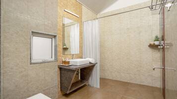 Un baño moderno con lavamanos de mármol, ducha con puerta de vidrio y espejo con marco de madera.