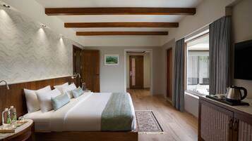 A modern hotel room with a large bed, wooden headboard, a flat-screen TV, and a window with curtains.