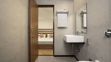 Un baño moderno con puerta de madera, un lavabo blanco, un espejo y un inodoro.