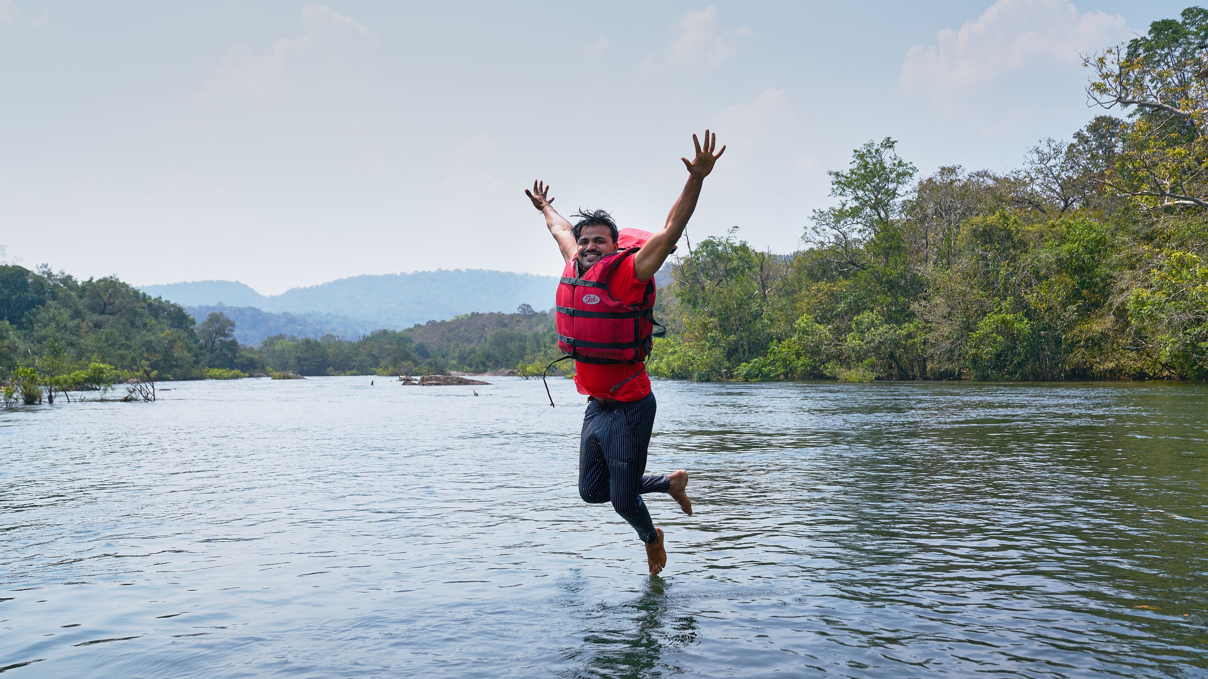A person jumping into a river wearing a life jacket.