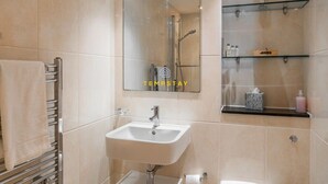 A modern bathroom with a sink, mirror, and glass shelves. - 1BR Apt Near Heathrow By Tempstay (Slough)