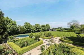Un jardin aménagé avec une piscine, un kiosque et une pelouse bien entretenue.