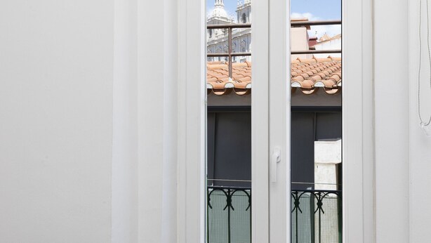 A view through a window with a metal balcony railing, a tiled roof, and a white building facade. - Charming Studio in Graça Overlooking the Tagus River (Lisboa)