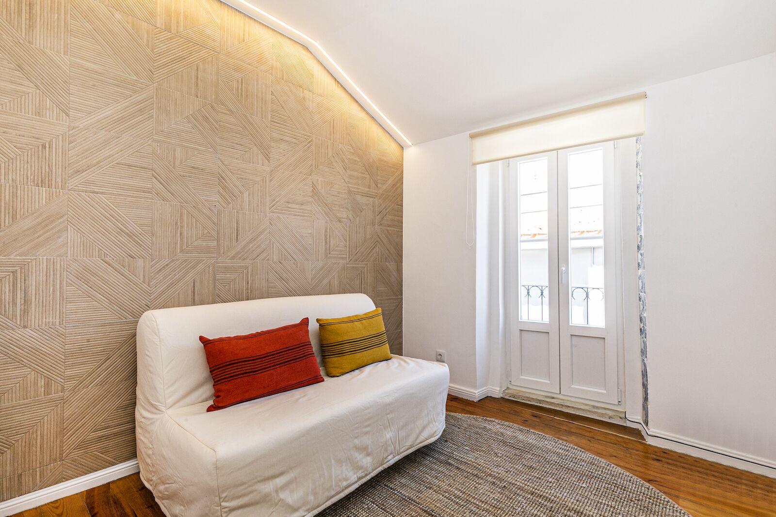 Un salon moderne avec un canapé blanc, un papier peint à motifs et une vue par la fenêtre.