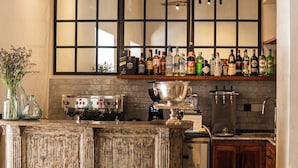 A bar area with a rustic wooden bar counter, a large mirror above the counter, and a variety of bottles and glasses on the shelves.