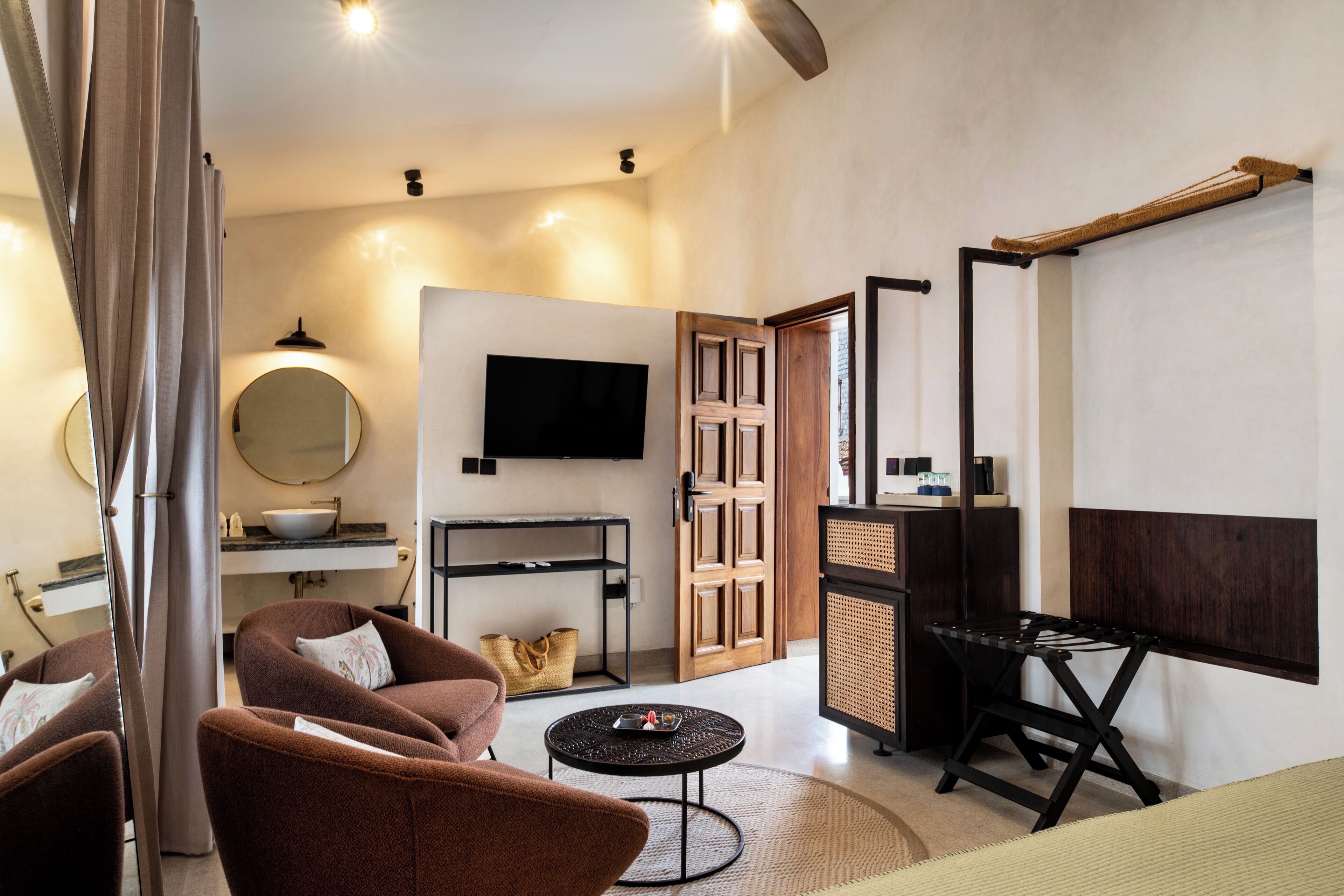 Una sala de estar moderna con un sofá, una mesita redonda, un televisor y un mueble de madera.
