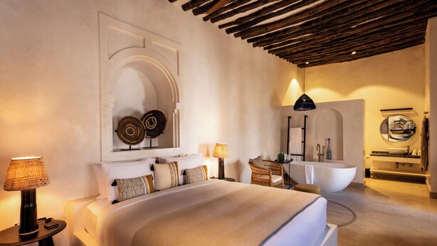 A spacious bedroom with a large bed, a sitting area, and a modern bathroom.
