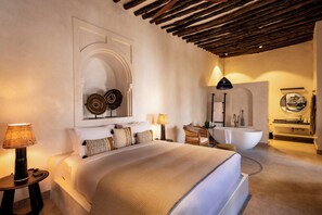 A spacious bedroom with a large bed, a sitting area, and a modern bathroom. - The Neela Boutique Hotel Stone Town (Zanzibar Town)