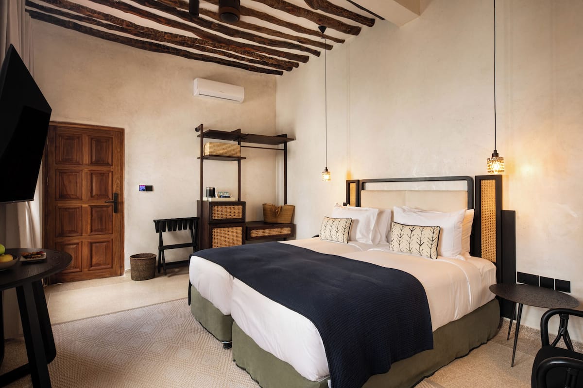 Un dormitorio con una cama grande, un armario de madera, una mesita y una lámpara colgante.