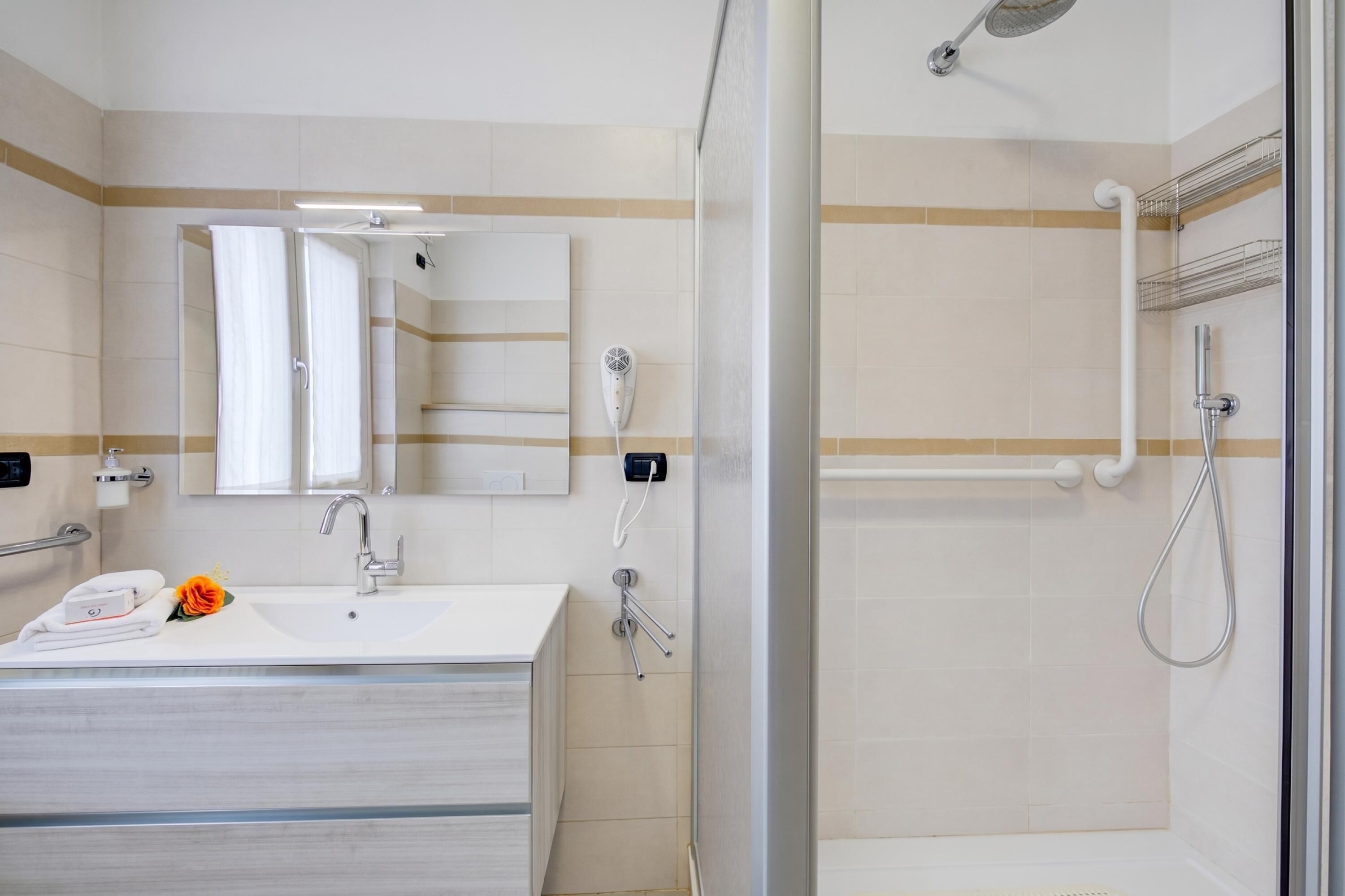A modern bathroom with a glass shower enclosure, a white sink, and a mirror.