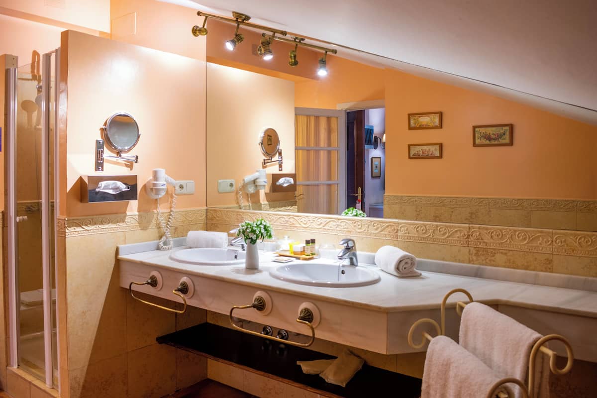 A bathroom with two sinks, a large mirror, a shower, and a towel rack.