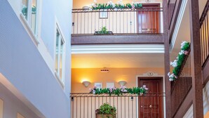 A multi-level atrium with a central seating area, multiple doors, and decorative plants. - Hotel Veracruz (Utrera)