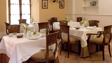 A dining area with multiple tables and chairs, white tablecloths, and floral centerpieces.