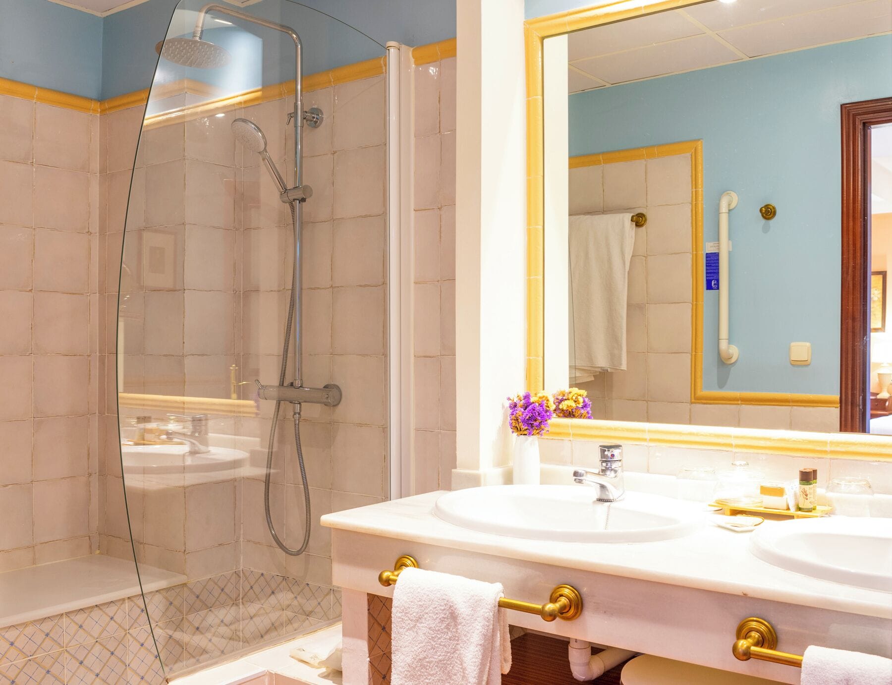 A modern bathroom with a glass-enclosed shower, dual sinks, and a large mirror.