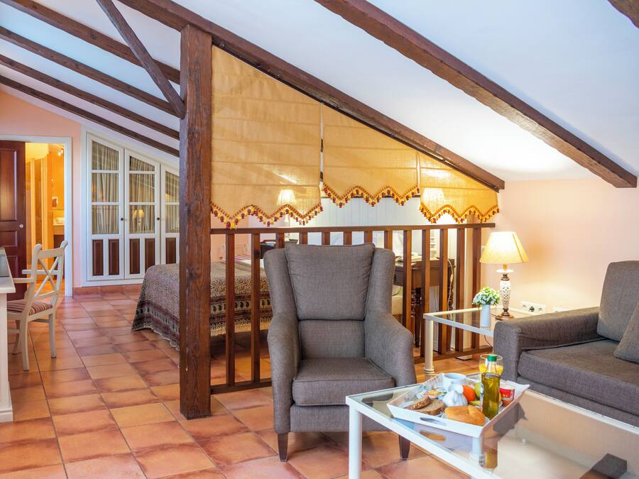 A cozy living room with a high ceiling, wooden beams, a patterned rug, and a breakfast tray on a table.
