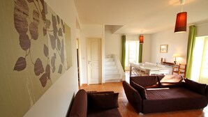 Ein Wohnzimmer mit braunen Sofas, ein Essbereich mit einem weißen Tisch und eine Treppe, die zu einer anderen Ebene führt.