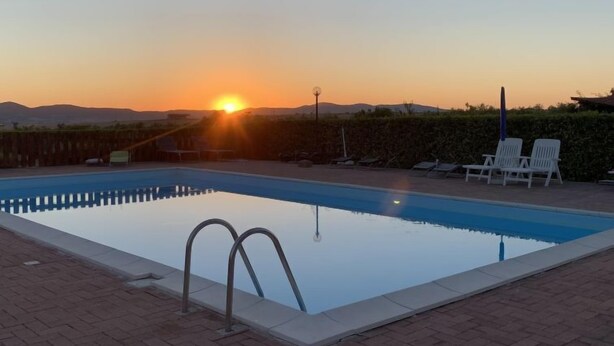A swimming pool with a sunset view, lounge chairs, and a clear sky. - Lavender by Interhome (Pomaia)