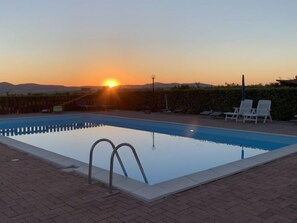 A swimming pool with a sunset view, lounge chairs, and a clear sky. - Lavender by Interhome (Pomaia)