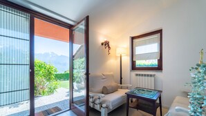 Una habitación con sofá, una mesita, una lámpara y vistas a las montañas a través de un ventanal corredero.