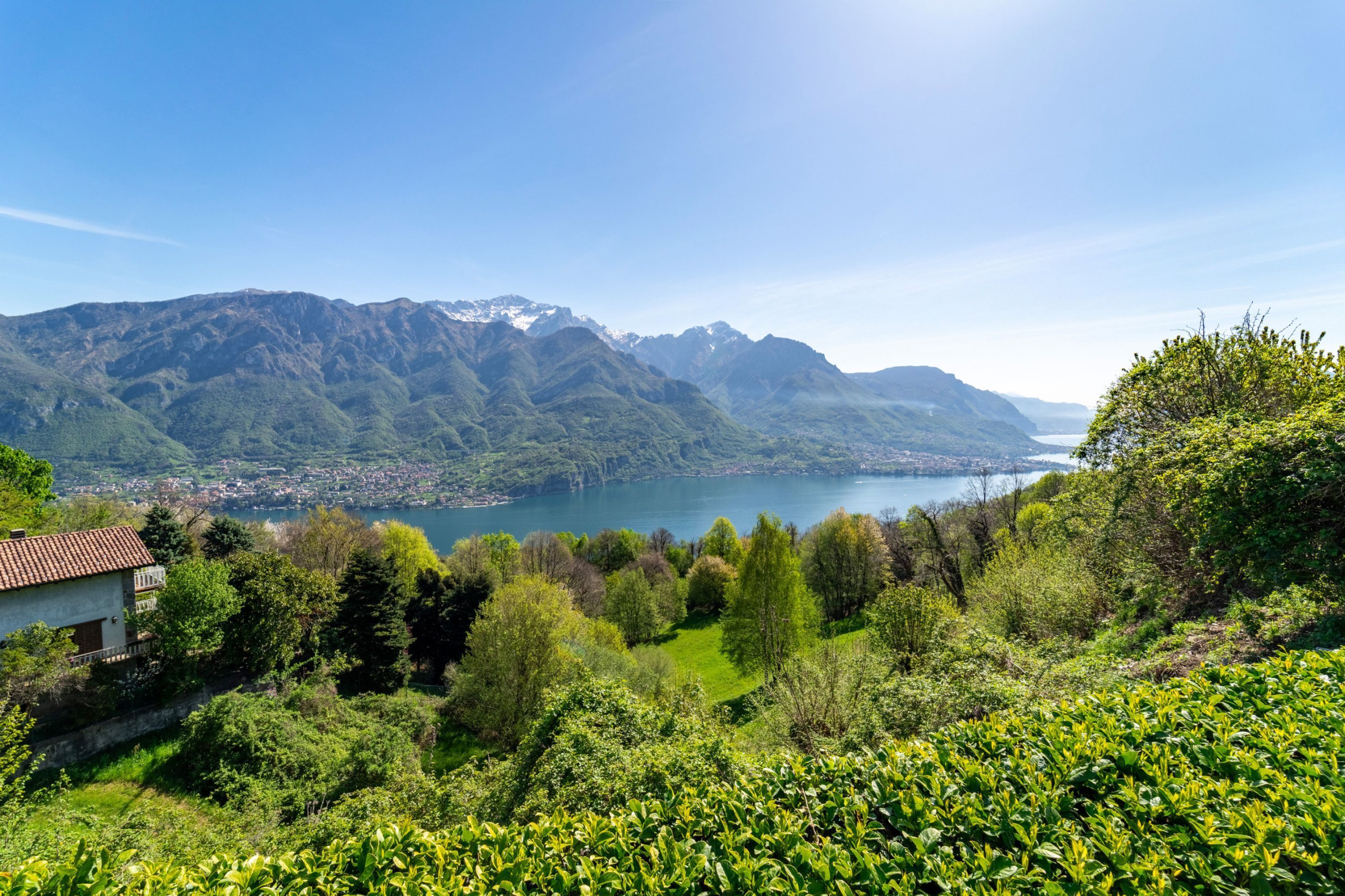 Un paysage montagneux avec un lac, de la végétation et un petit bâtiment.