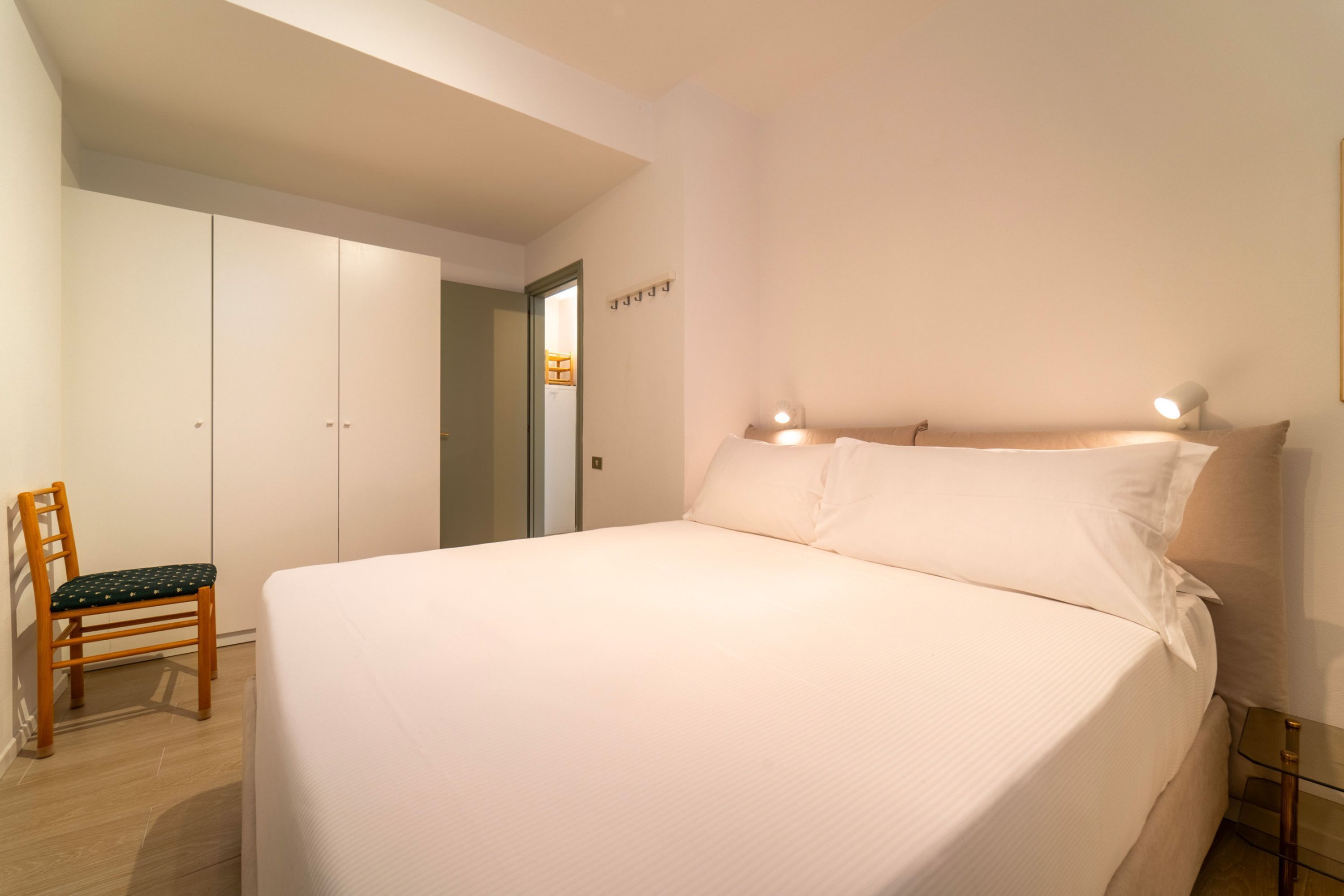 Une chambre à coucher avec un grand lit, une chaise, une armoire et une table de chevet.