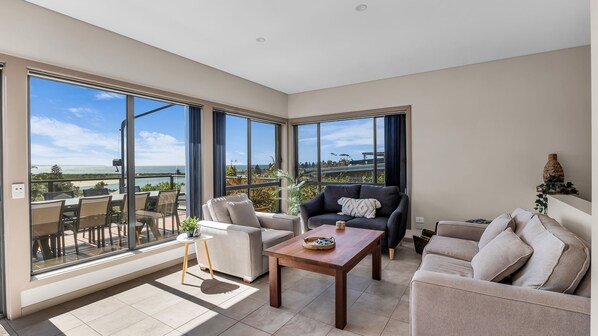 A spacious living area with a balcony, large windows, and a view of the outdoors.