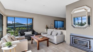 A modern living room with a fireplace, large windows, and a view of the outdoors.