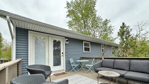Une terrasse couverte avec des fauteuils en osier, un canapé et une petite table.