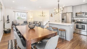 Une cuisine moderne dotée d’appareils électroménagers en acier inoxydable, d’une table à manger en bois et d’un îlot central avec des tabourets de bar.