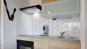 A modern kitchen with white tiled backsplash, stainless steel appliances, and wooden cabinets. - Les Mas de La Mer by Interhome (Saint Cyprien)