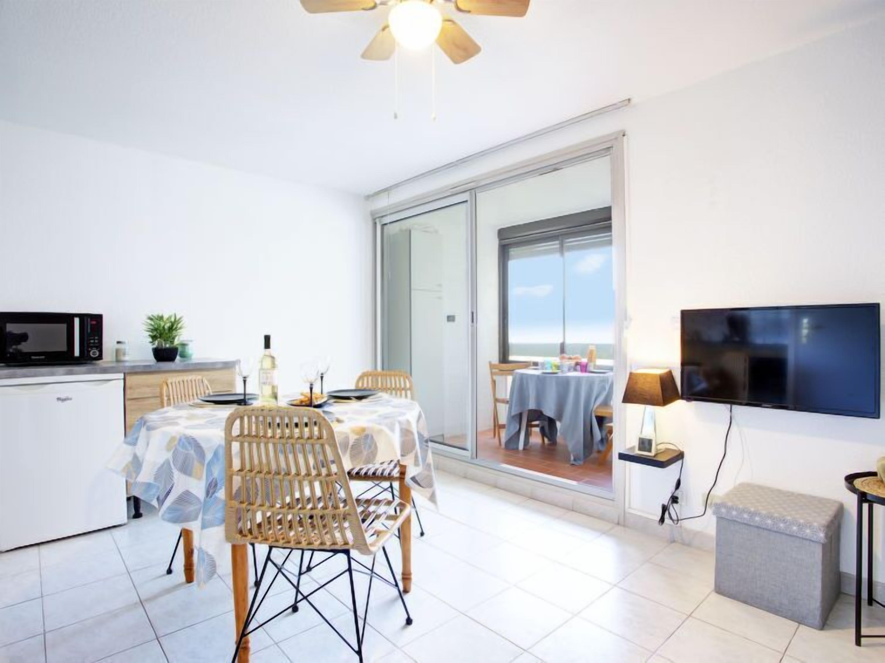 Eine moderne Küche mit Mikrowelle, Esstisch, Stühlen und Deckenventilator.