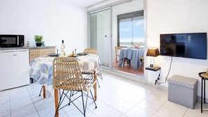 A modern kitchen with a microwave, dining table, chairs, and a ceiling fan. - Les Mas de La Mer by Interhome (Saint Cyprien)