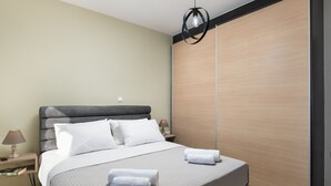 A modern bedroom with a large bed, two bedside tables with lamps, and a wooden wardrobe. - The cozy nook (Chorafakia)
