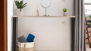 A bathroom with a mirror, two potted plants, a reed diffuser, and a basket with towels. - The cozy nook (Chorafakia)
